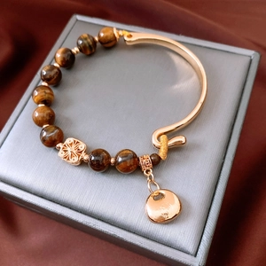 Detail of 18K gold plated tiger eye bead bracelet with round pendant on jewelry box