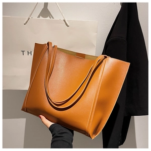 Detailed view of a large brown leather tote bag held against a stylish shopping background