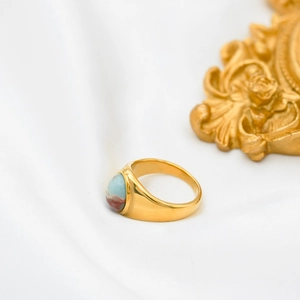 Close-up of gold-plated titanium ring featuring a natural oval agate stone on white silk