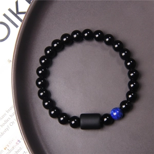 Detail of stone bead bracelet with Pisces zodiac sign charm on dark grey tray