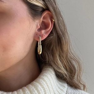 18K gold-plated safety pin earrings with pave zircon accents on a female model