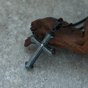 Close-up of black stainless steel cross pendant with engraved Lord's Prayer text
