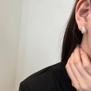 Close-up of elegant gold teardrop earrings with pavé crystals on a female model