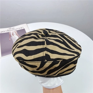 Dettaglio del cappello basco in tela beige con stampa zebra e finiture nere chic