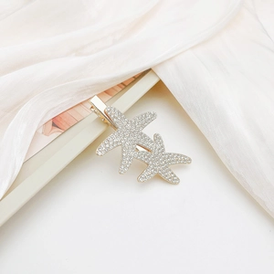 Macro detail of a golden starfish hair clip with sparkling rhinestones on silk