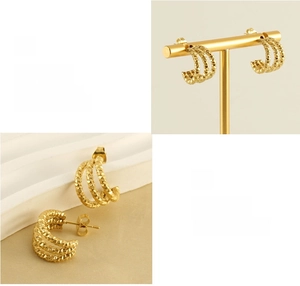 Detail of gold U-shaped earrings with layered wave textures and polished metallic luster