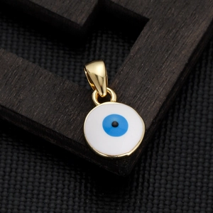 Macro shot of gold-plated evil eye charm pendant on a wooden frame with blue enamel detail