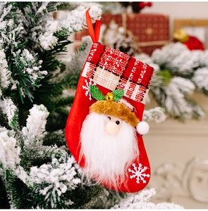 Détail d'une chaussette de Noël avec Père Noël suspendue à une branche enneigée