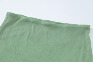 Macro view of grass green knitted fabric texture and fine stitching on top edge