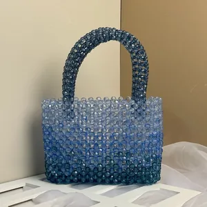 Detail of handmade acrylic beaded handbag with blue gradient beads and clear handle