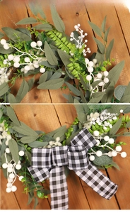 Detail of faux white berries and green leaves wreath with black and white plaid bow
