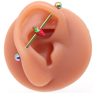 Détail d'un piercing industriel avec breloque fraise rouge sur un modèle d'oreille