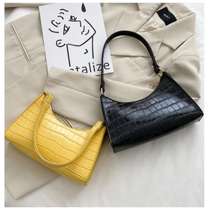 Close-up of black and yellow crocodile pattern baguette bags with gold hardware details