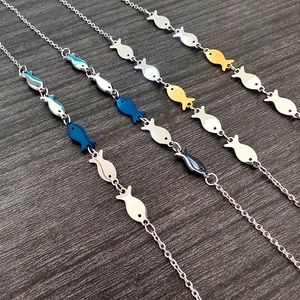 Macro shot of fish charms in silver, gold, and blue gradients on a dark wood background