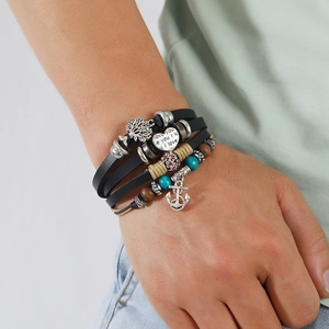 Mehrlagiges Lederarmband mit Lebensbaum, Herz und Anker Anhängern am Handgelenk des Models