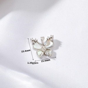 Detail showing white butterfly pendant dimensions 15.4mm x 15.9mm on textured fabric