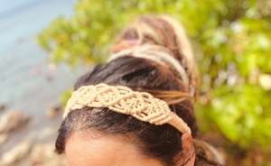 Close-up of a handmade beige macrame headband worn by a model in a natural outdoor setting