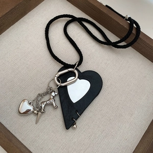 Detail of leather heart pendant with silver metallic dog charm on black woven cord