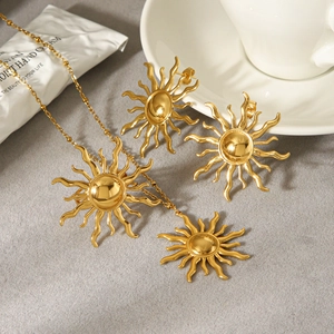 18k gold plated sun pendant necklace and earrings set on minimalist grey background