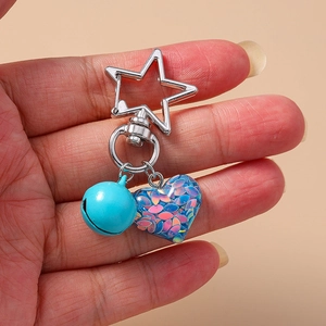 Detail of blue bell and heart resin keychain with colorful sequins on a star clasp