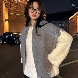 Women's winter grey knit scarf with tassels and white sweater in outdoor night street style