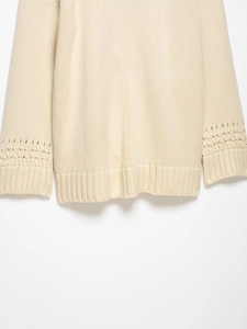 Detail of cream knit cardigan featuring intricate hollow-out patterns on the cuffs