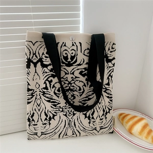 Detail of the black and white floral knit tote bag featuring a secure silver magnetic buckle
