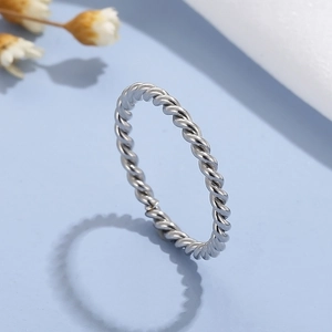 Close-up of a silver minimalist stainless steel twisted rope ring on a blue surface