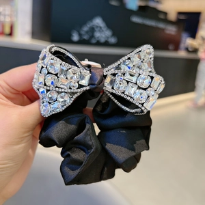 Luxurious black satin scrunchie featuring a large bow fully covered in sparkling crystals