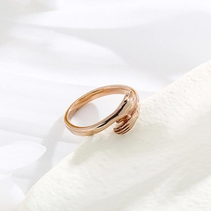 Macro view of rose gold embrace ring on white silk, showing hands hugging design detail