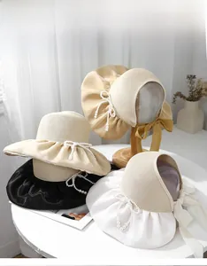 Detail of straw sun hats with pearl bow accents and elegant ribbon ties in various colors