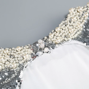 Close-up of silver sequins, white faux pearls, and rhinestones on a backless evening dress