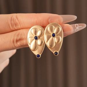 Detailed view of vintage gold floral earrings featuring teardrop blue crystal accents