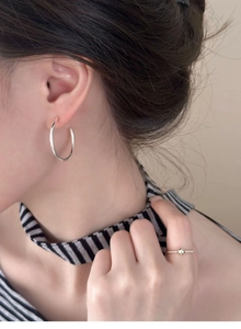 Close-up of elegant silver circular C-shaped earrings on model with minimalist ring