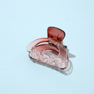 Macro shot of a red-brown transparent acetate hair claw clip on a light blue background