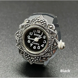 Macro shot of a vintage silver ring watch with black dial and embossed metal texture