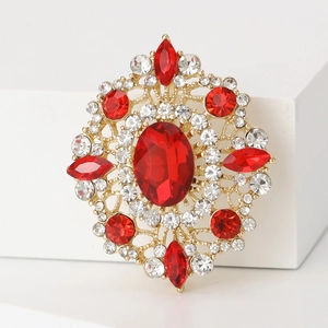Vintage gold brooch with oval red crystal and rhinestones on a white pedestal