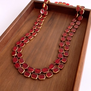 Detail of a vintage double-layer necklace with deep red glass beads in a wood tray