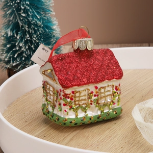 Close-up of a Christmas house ornament with red glitter roof and festive ribbon