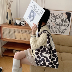 Detail of corduroy heart print tote bag showing texture and brand label on shoulder strap