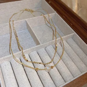 Elegant gold double-layered necklace featuring a pearlescent bead and sequin chain detail