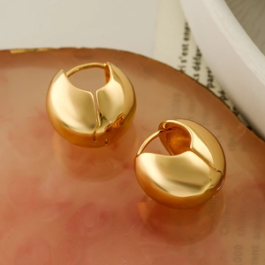 Minimalist irregular geometric gold spherical hoop earrings on a decorative warm tray
