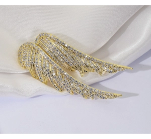 Macro detail of elegant golden angel wing brooch with sparkling micro-pave zircons