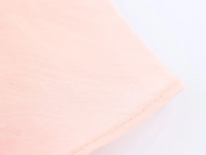 Macro shot of double-hemmed sewing detail on the light pink fabric midi dress
