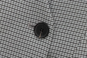 Macro shot of houndstooth pattern fabric with a black round four-hole resin button detail