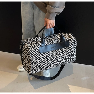 Dettaglio borsa da viaggio con motivi monogramma bianchi e neri e manici in pelle