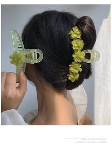 Detail of light green floral hair claw clip worn by a model with metal tassel accents
