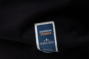 Close-up of black V-neck knit sweater featuring colorful fashion labels and fabric texture