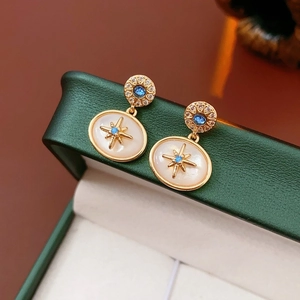 Dettaglio di orecchini vintage dorati con cristalli blu e pendente a stella bianco