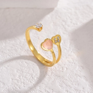 Golden titanium heart ring with pink stone and clover diamond setting on white background